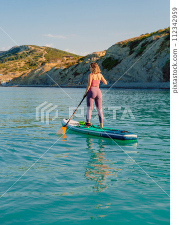 Woman on stand up paddle board, quiet ocean on sunny summer day. Relaxing on sea 112342959
