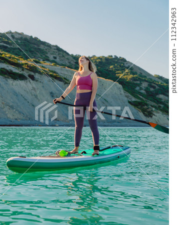 Enjoying woman on stand up paddle board at sea. Woman on SUP board in ocean. 112342963