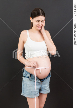 pregnant woman using tape measure to check baby development and the growth of belly. Inch measurement 112343386
