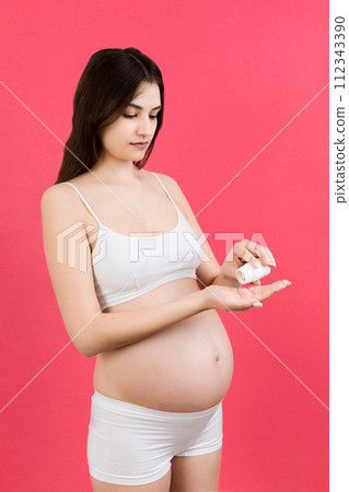 pregnant woman holding a bottle and a pile of pills in hands at colorful background with copy space. Healthcare concept 112343390