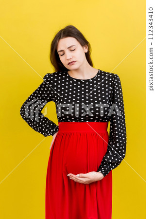 Pregnant woman with a pain in her back on colored Background isolated Pregnant woman with a pain in her back on colored Background isolated 112343410