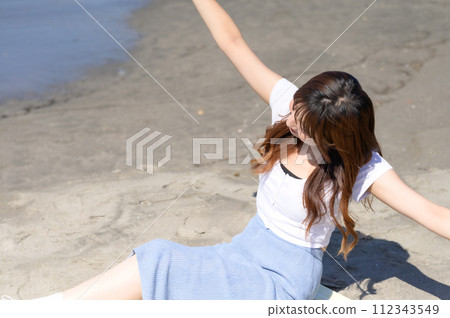 Woman resting on the sandy beach with a drink in hand Woman resting on the sandy beach with a drink in hand 112343549