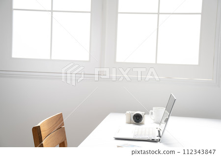 Image with a laptop and digital camera next to a white window 112343847