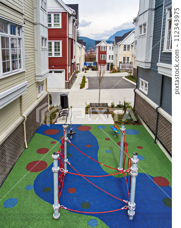 Playground space in residential area of townhouses on overcast sky background Playground space in residential area of townhouses on overcast sky background 112343975