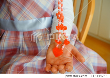 A 4th grade elementary school girl is enjoying playing with beads at home. 112344258