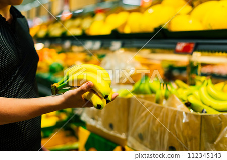 Boy holding a bunch of bananas in the supermarket 112345143