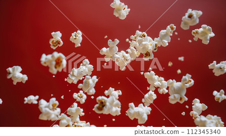 Advertising shot of flying popcorn peaces in the air, close up shot on neutral dark red background 112345340