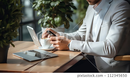 Businessman in white suit jacket using smartphone and laptop in 112345650