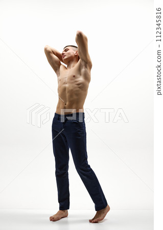 Full-length image of handsome, confident, shirtless man with muscular body posing in jeans isolated over white studio background Full-length image of handsome, confident, shirtless man with muscular body posing in jeans isolated over white studio background 112345816