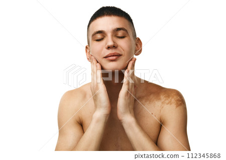 Young handsome man standing shirtless, taking care after skin, washing face isolated over white studio background 112345868