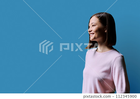 Profile portrait of young smiling woman on blue background Profile portrait of young smiling woman on blue background 112345900