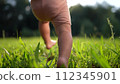baby takes first steps in the park. happy family kid dream concept. dad teaches his son to walk takes the first steps in the park on green grass. baby son taking first lifestyle steps 112345901