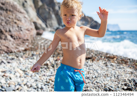 Beautiful blond child 2.5 years old in swimming trunks at the sea on a sunny warm summer day 112346494
