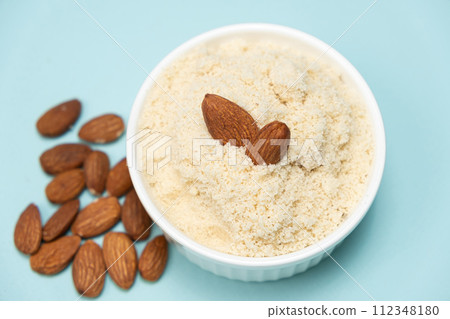 Almond flour and almonds on a light blue background Almond flour and almonds on a light blue background 112348180