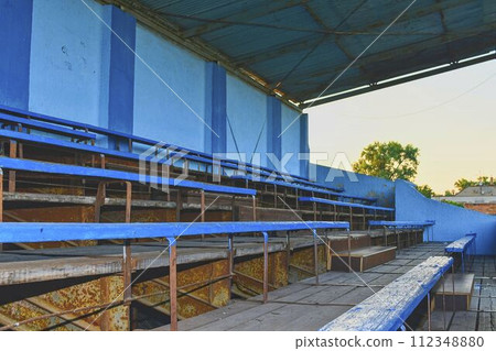 Old grandstand seats. Vintage tone. Old blue wooden grandstand stadium 112348880