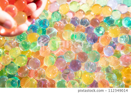 Colored balls of hydrogel touch children's hands. Sensory sensations. 112349014