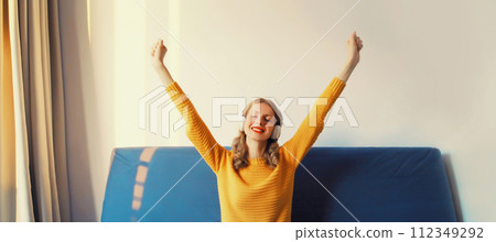 Happy cheerful young woman listening to music with headphones having fun at home Happy cheerful young woman listening to music with headphones having fun at home 112349292
