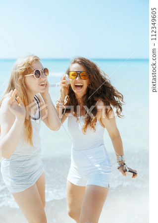 smiling stylish mother and child on beach dancing 112349605