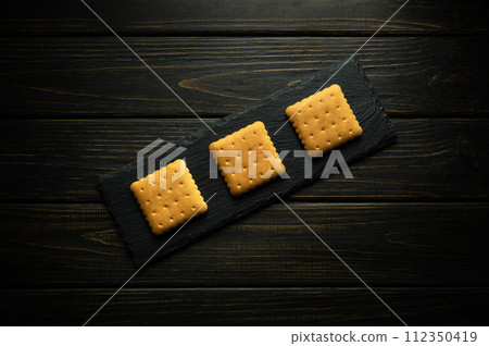 Square cookies on a serving board prepared for dessert. Sweet snack concept on dark background 112350419