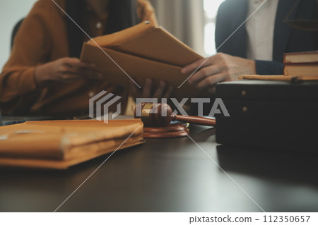 Justice and Law concept. Legal counsel presents to the client a signed contract with gavel and legal law or legal having team meeting at law firm in background Justice and Law concept. Legal counsel presents to the client a signed contract with gavel and legal law or legal having team meeting at law firm in background 112350657