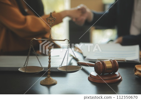 Justice and Law concept. Legal counsel presents to the client a signed contract with gavel and legal law or legal having team meeting at law firm in background Justice and Law concept. Legal counsel presents to the client a signed contract with gavel and legal law or legal having team meeting at law firm in background 112350670