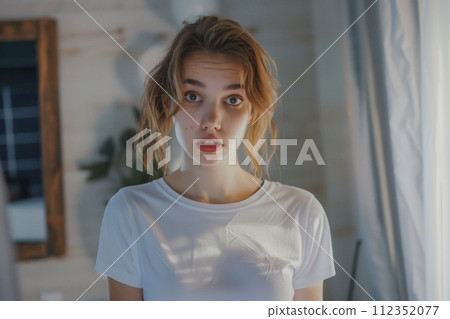 Young woman with acne inflammation on her face looking in the mirror at home 112352077