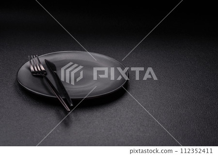 Cutlery fork, knife and spoon on a dark textured concrete background 112352411