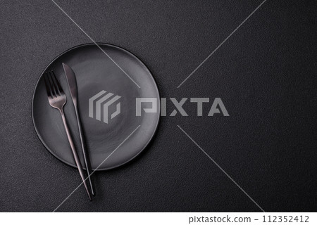 Cutlery fork, knife and spoon on a dark textured concrete background 112352412