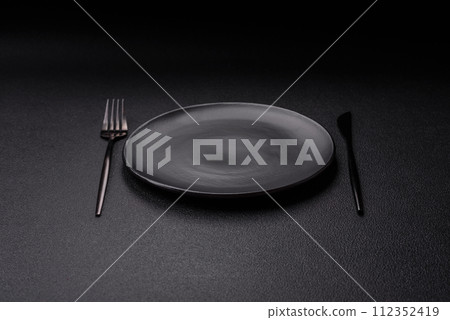 Cutlery fork, knife and spoon on a dark textured concrete background Cutlery fork, knife and spoon on a dark textured concrete background 112352419