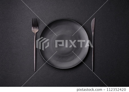 Cutlery fork, knife and spoon on a dark textured concrete background Cutlery fork, knife and spoon on a dark textured concrete background 112352420