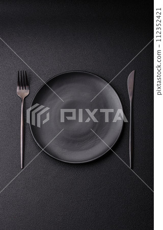 Cutlery fork, knife and spoon on a dark textured concrete background 112352421