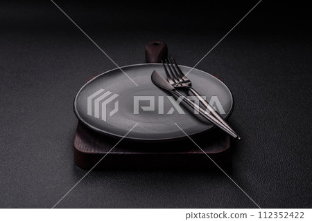 Cutlery fork, knife and spoon on a dark textured concrete background 112352422