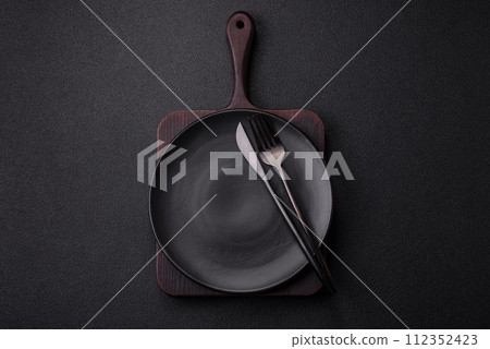 Cutlery fork, knife and spoon on a dark textured concrete background 112352423