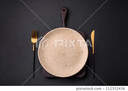 Cutlery fork, knife and spoon on a dark textured concrete background 112352436