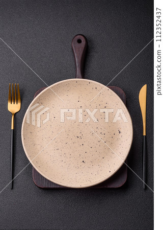 Cutlery fork, knife and spoon on a dark textured concrete background 112352437