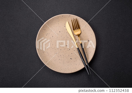 Cutlery fork, knife and spoon on a dark textured concrete background Cutlery fork, knife and spoon on a dark textured concrete background 112352438
