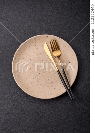 Cutlery fork, knife and spoon on a dark textured concrete background Cutlery fork, knife and spoon on a dark textured concrete background 112352440
