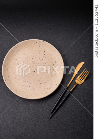 Cutlery fork, knife and spoon on a dark textured concrete background Cutlery fork, knife and spoon on a dark textured concrete background 112352443