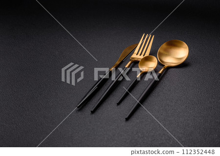 Cutlery fork, knife and spoon on a dark textured concrete background Cutlery fork, knife and spoon on a dark textured concrete background 112352448