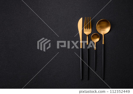 Cutlery fork, knife and spoon on a dark textured concrete background Cutlery fork, knife and spoon on a dark textured concrete background 112352449