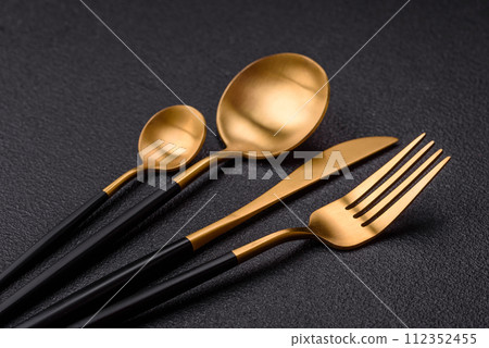Cutlery fork, knife and spoon on a dark textured concrete background Cutlery fork, knife and spoon on a dark textured concrete background 112352455