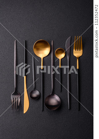 Cutlery fork, knife and spoon on a dark textured concrete background 112352472