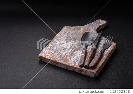 Cutlery fork, knife and spoon on a dark textured concrete background Cutlery fork, knife and spoon on a dark textured concrete background 112352568