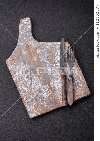 Cutlery fork, knife and spoon on a dark textured concrete background 112352577