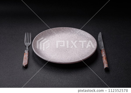 Cutlery fork, knife and spoon on a dark textured concrete background Cutlery fork, knife and spoon on a dark textured concrete background 112352578