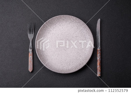 Cutlery fork, knife and spoon on a dark textured concrete background Cutlery fork, knife and spoon on a dark textured concrete background 112352579
