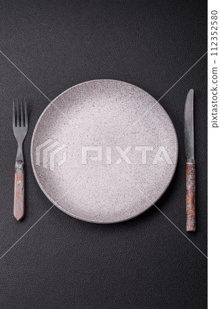 Cutlery fork, knife and spoon on a dark textured concrete background Cutlery fork, knife and spoon on a dark textured concrete background 112352580