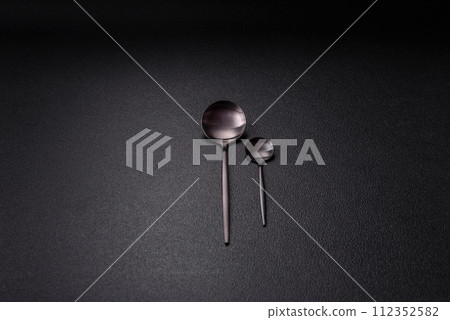 Cutlery fork, knife and spoon on a dark textured concrete background Cutlery fork, knife and spoon on a dark textured concrete background 112352582