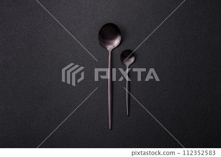 Cutlery fork, knife and spoon on a dark textured concrete background 112352583