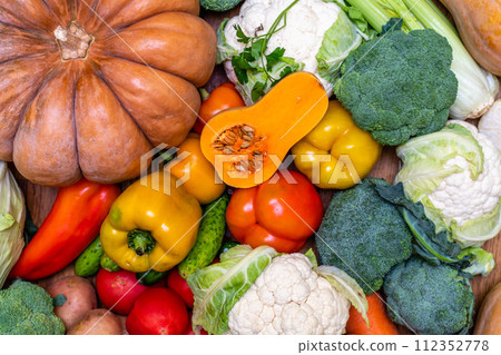 Various vegetables are laid out on a wooden table. Large assortment of vegetables food. pumpkin cabbage broccoli pepper tomatoes carrots and others Various vegetables are laid out on a wooden table. Large assortment of vegetables food. pumpkin cabbage broccoli pepper tomatoes carrots and others 112352778